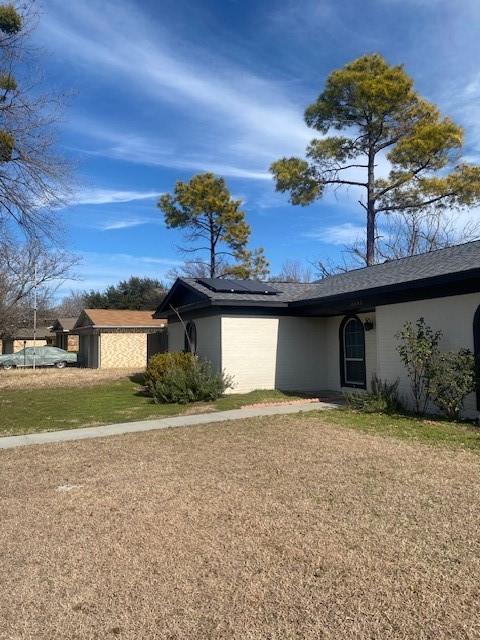 ranch-style house featuring a front yard and solar panels