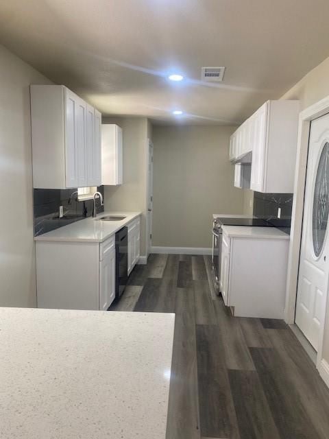 kitchen with dark wood-type flooring, sink, tasteful backsplash, black dishwasher, and white cabinets