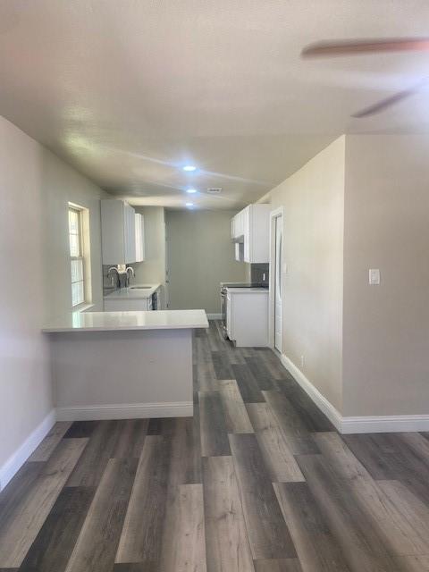 kitchen with white cabinetry, sink, dark wood-type flooring, and kitchen peninsula