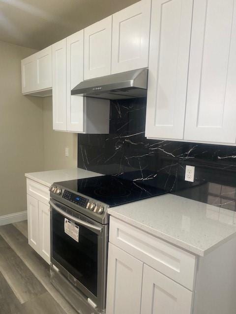 kitchen featuring white cabinetry, light stone counters, electric range, and backsplash