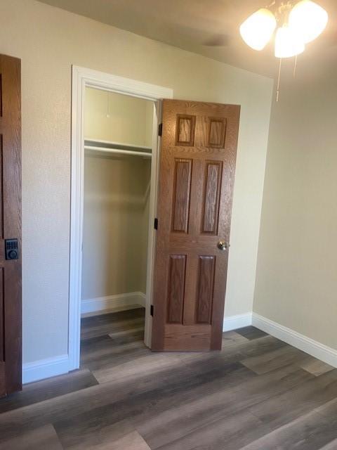 unfurnished bedroom featuring dark wood-type flooring, a closet, and ceiling fan