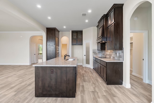 kitchen featuring light stone counters, sink, a kitchen island with sink, and light wood-type flooring