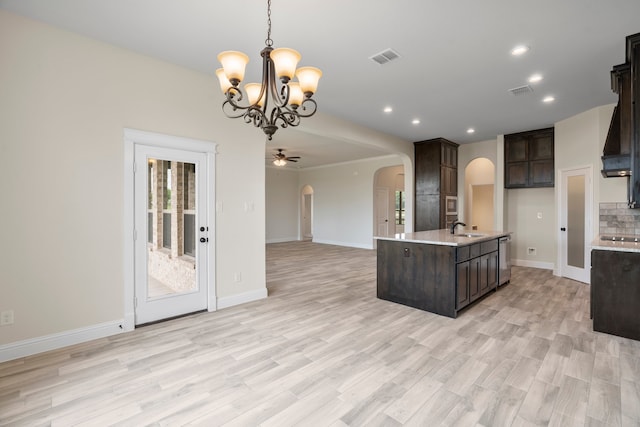 kitchen featuring sink, a center island with sink, decorative light fixtures, and dark brown cabinetry