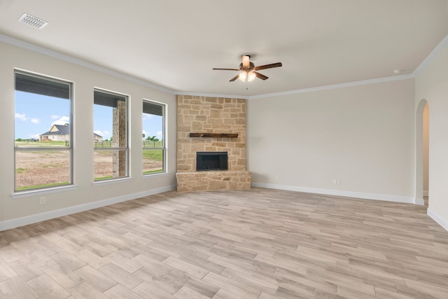 unfurnished living room with light hardwood / wood-style flooring, ceiling fan, a stone fireplace, and ornamental molding