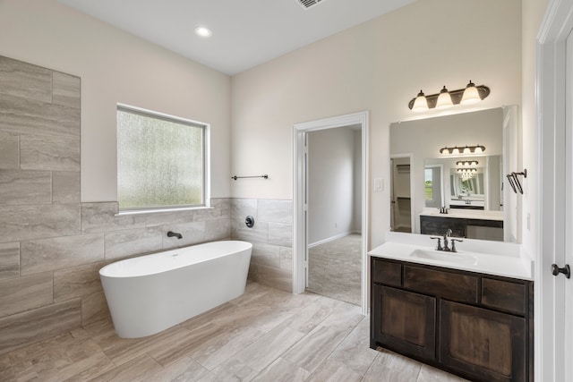 bathroom with vanity, tile walls, and a bathing tub