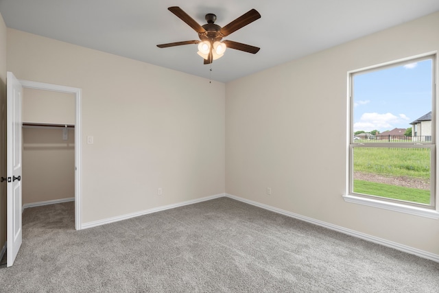 unfurnished bedroom featuring a walk in closet, ceiling fan, multiple windows, and a closet