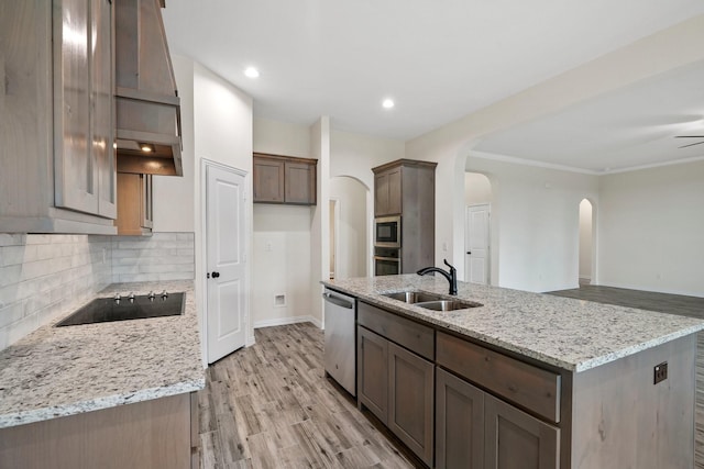 kitchen with light stone counters, sink, appliances with stainless steel finishes, and a kitchen island with sink