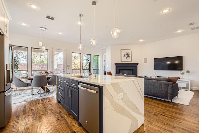 kitchen with white cabinetry, hanging light fixtures, sink, stainless steel appliances, and light stone counters