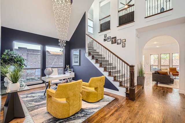 interior space featuring wood-type flooring, a towering ceiling, and a notable chandelier