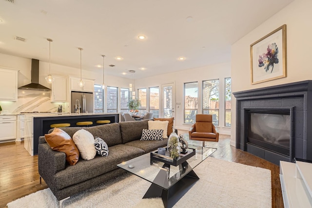 living room featuring sink, hardwood / wood-style flooring, and a healthy amount of sunlight