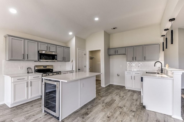 kitchen with sink, beverage cooler, appliances with stainless steel finishes, and gray cabinets