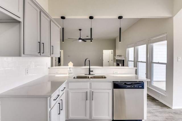 kitchen featuring kitchen peninsula, dishwasher, ceiling fan, sink, and decorative light fixtures