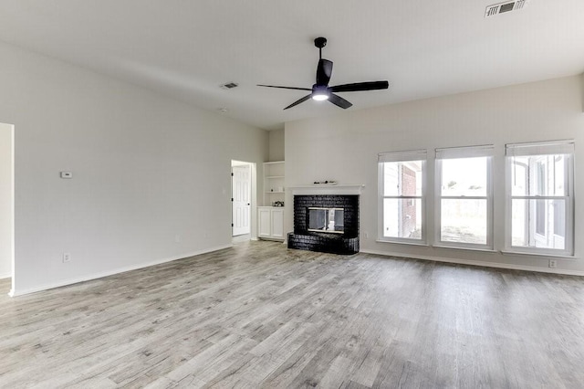 unfurnished living room with a brick fireplace, ceiling fan, and light wood-type flooring