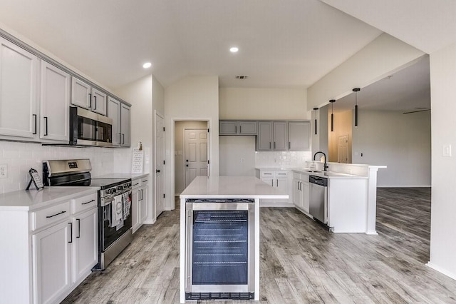 kitchen featuring beverage cooler, decorative light fixtures, stainless steel appliances, sink, and gray cabinetry