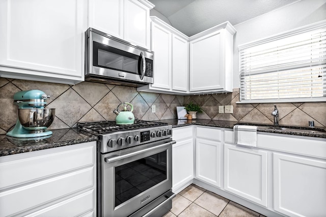 kitchen featuring light tile patterned floors, white cabinets, decorative backsplash, stainless steel appliances, and a sink