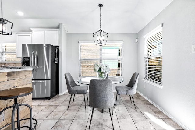 dining area featuring light tile patterned floors, baseboards, and a notable chandelier