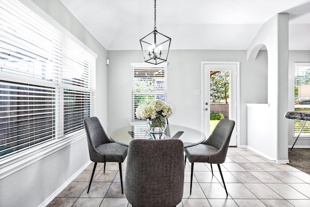 dining space featuring light tile patterned flooring, vaulted ceiling, a healthy amount of sunlight, and an inviting chandelier