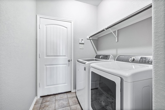 washroom with laundry area, light tile patterned floors, baseboards, and separate washer and dryer