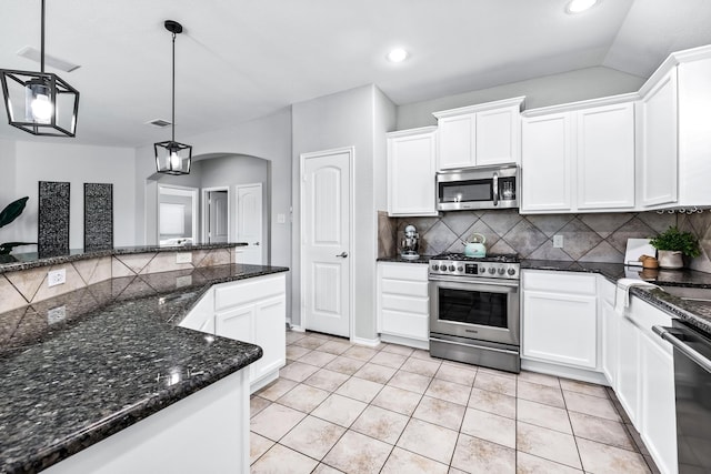 kitchen with arched walkways, white cabinets, decorative backsplash, appliances with stainless steel finishes, and light tile patterned flooring