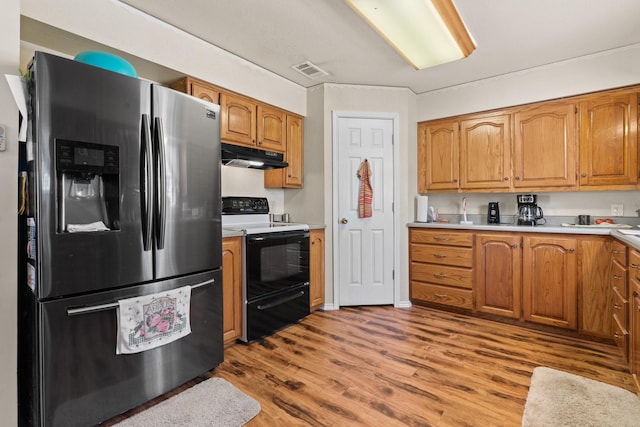 kitchen featuring light wood-type flooring, electric stove, and stainless steel fridge