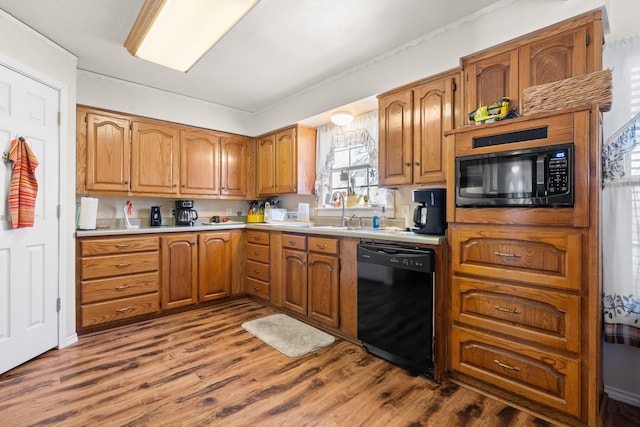 kitchen featuring black appliances, wood-type flooring, and sink