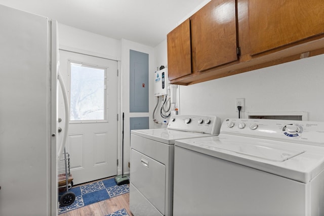 laundry area with light hardwood / wood-style floors, cabinets, electric panel, and washing machine and dryer