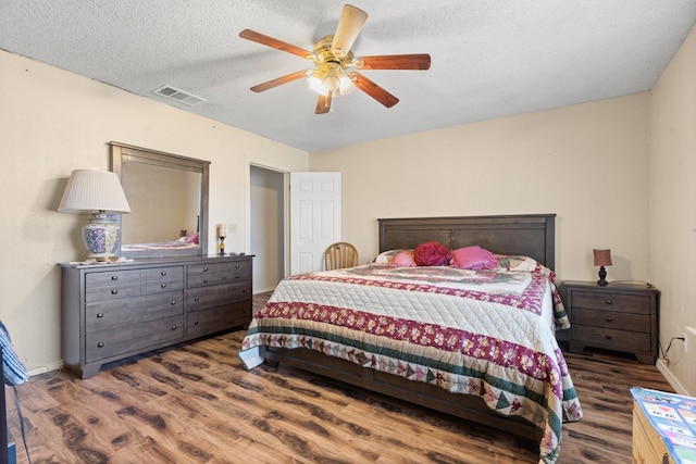 bedroom with ceiling fan, dark hardwood / wood-style floors, and a textured ceiling