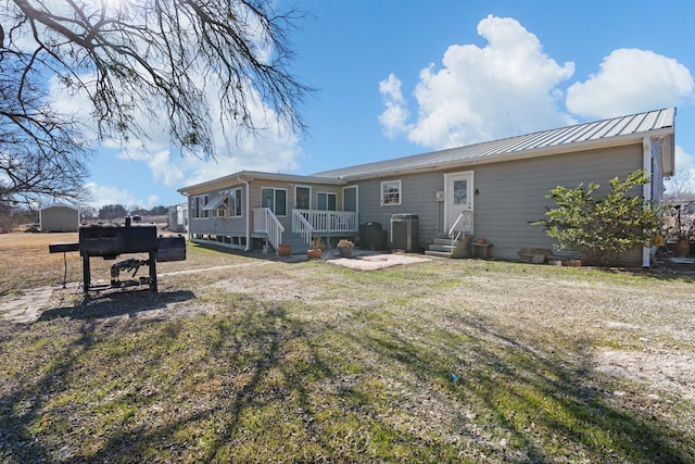 back of property featuring a yard and central AC