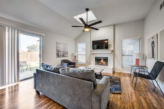 living room featuring ceiling fan, hardwood / wood-style flooring, vaulted ceiling, and a brick fireplace