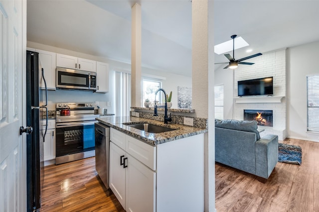 kitchen with wood-type flooring, sink, white cabinetry, dark stone counters, and stainless steel appliances