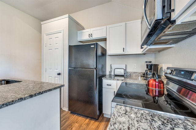 kitchen with stone counters, white cabinets, stainless steel appliances, and light wood-type flooring