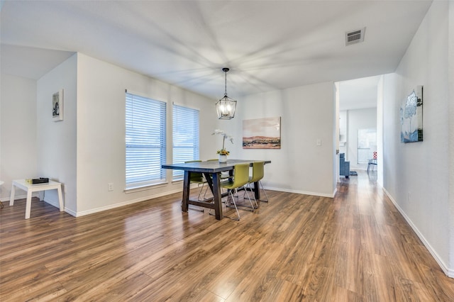 dining space with wood-type flooring and a notable chandelier