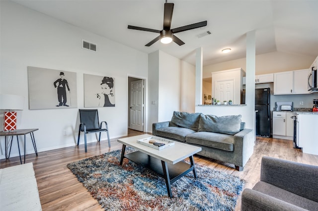 living room featuring ceiling fan, light hardwood / wood-style flooring, and lofted ceiling