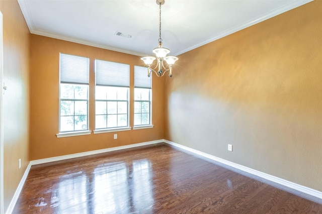 spare room featuring dark wood-type flooring, crown molding, and a chandelier