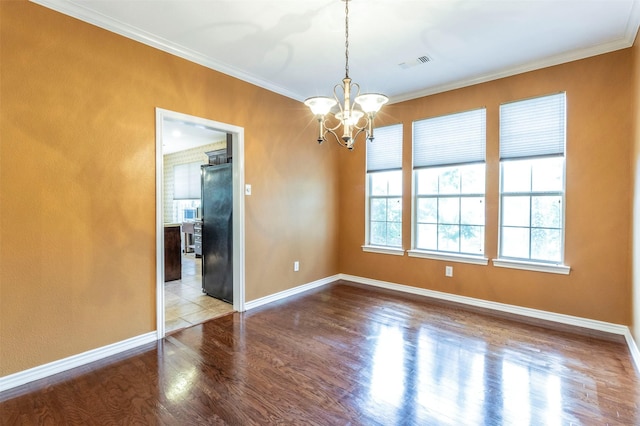 spare room featuring crown molding, an inviting chandelier, and wood-type flooring