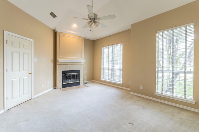 unfurnished living room with ceiling fan, a tile fireplace, light carpet, and lofted ceiling