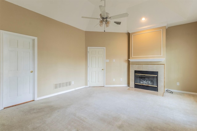 unfurnished living room with a tiled fireplace, light colored carpet, and ceiling fan