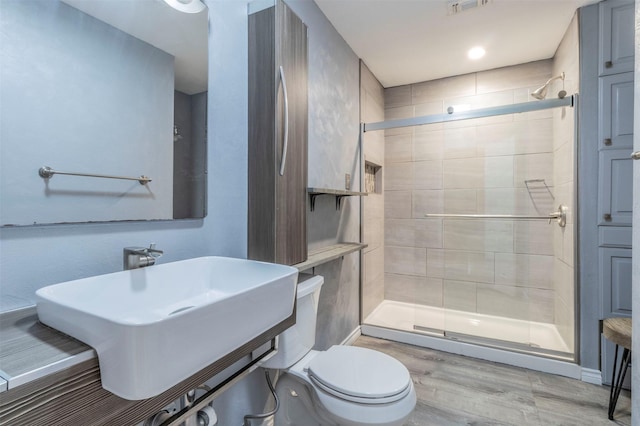 bathroom with a shower with shower door, sink, wood-type flooring, and toilet