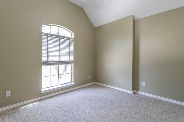 carpeted empty room featuring vaulted ceiling