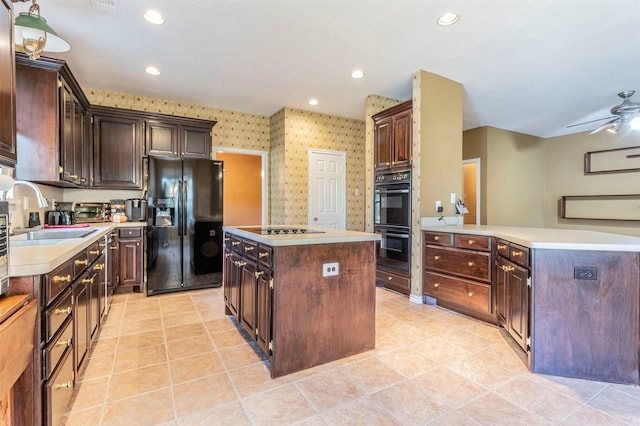 kitchen with black appliances, a kitchen island, dark brown cabinetry, and sink