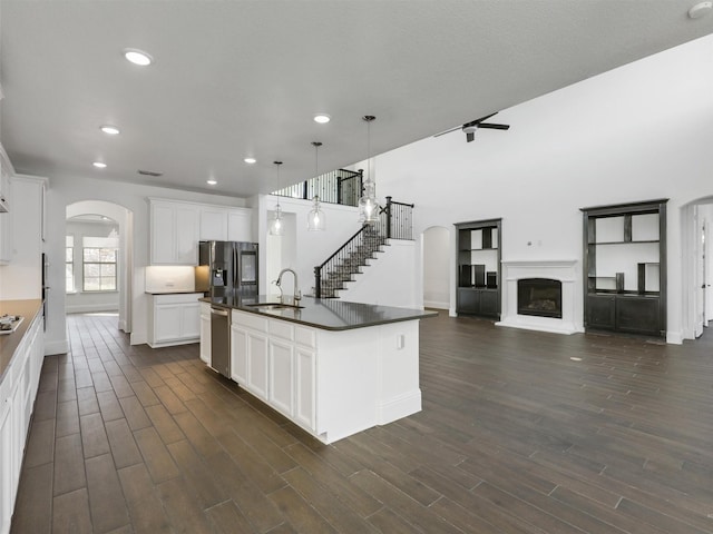 kitchen featuring white cabinetry, sink, decorative light fixtures, and a center island with sink