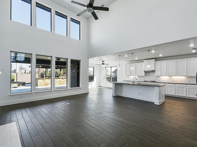 unfurnished living room featuring ceiling fan, dark hardwood / wood-style flooring, and sink