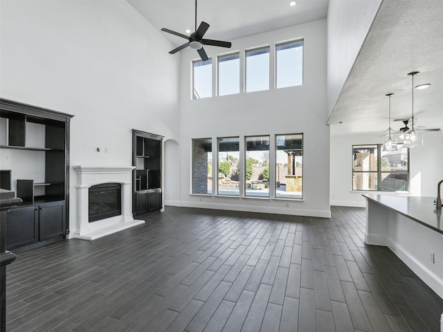 13750 Fernando Rd, Frisco, TX 75035 - unfurnished living room with ceiling fan, a towering ceiling, plenty of natural light, a glass covered fireplace, and recessed lighting