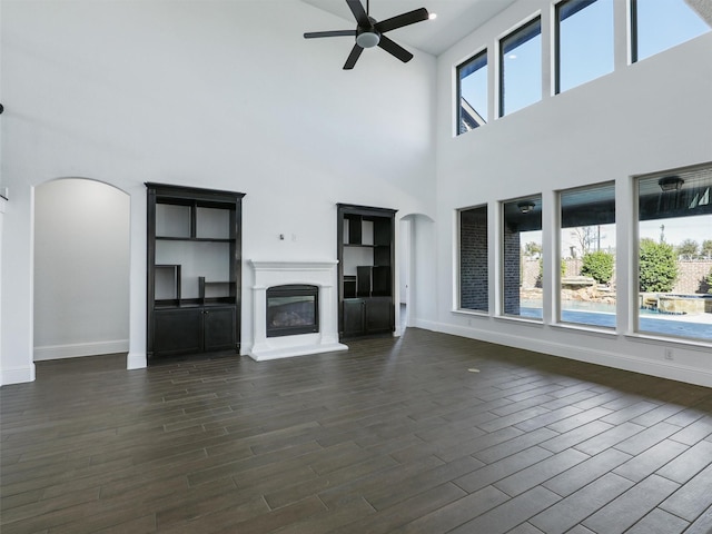 13750 Fernando Rd, Frisco, TX 75035 - unfurnished living room with arched walkways, ceiling fan, dark wood finished floors, a towering ceiling, and baseboards