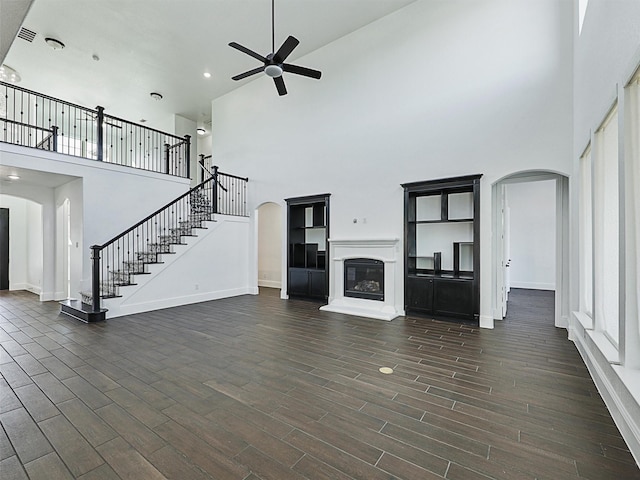 13750 Fernando Rd, Frisco, TX 75035 - unfurnished living room with a high ceiling, arched walkways, a ceiling fan, a glass covered fireplace, and baseboards