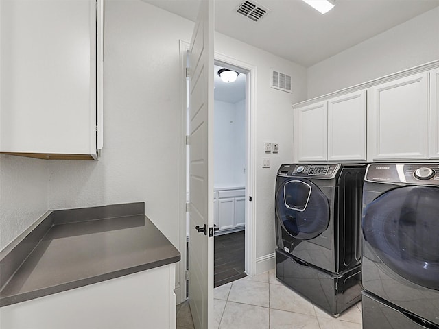 laundry area with cabinets, washing machine and dryer, and light tile patterned floors