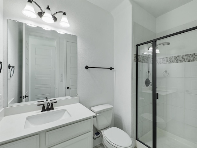 bathroom featuring a shower with door, vanity, and toilet