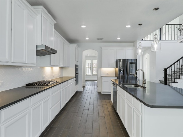 13750 Fernando Rd, Frisco, TX 75035 - kitchen with arched walkways, stainless steel appliances, dark countertops, under cabinet range hood, and a sink