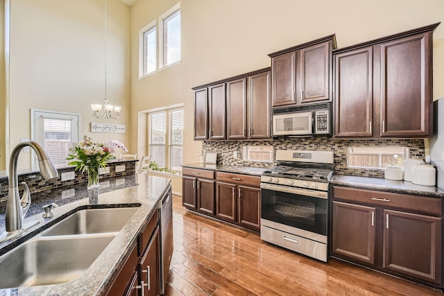 kitchen with sink, decorative light fixtures, light hardwood / wood-style flooring, appliances with stainless steel finishes, and a notable chandelier