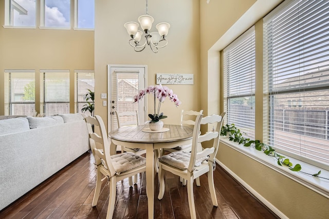 dining area with a high ceiling, a chandelier, and dark hardwood / wood-style flooring